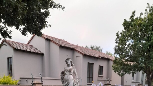 Una statua in un giardino, con un edificio sullo sfondo.