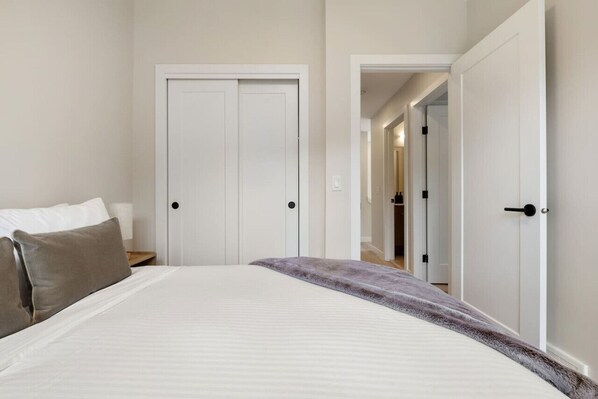 Un dormitorio con una cama, dos puertas y un pasillo que conduce a otra habitación.
