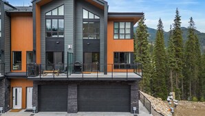 Een modern huis met twee verdiepingen, een garage, grote ramen en een balkon.