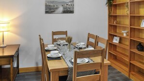 A dining area with a wooden table set for four, chairs, a lamp, and a bookshelf with decorative items. - New House Farm - UKC6912 (Cowan Bridge, near Kirkby Lonsdale)