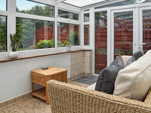 A conservatory with a glass door, a wooden bench, and a wicker sofa. - New House Farm - UKC6912 (Cowan Bridge, near Kirkby Lonsdale)