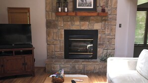 A living room with a stone fireplace, a television, and a white sofa. - Royal View your holiday escape on Table Rock Lake near Branson Attractions. (Lampe)