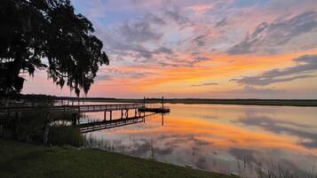A calm lake at sunset with a wooden dock extending into the water.