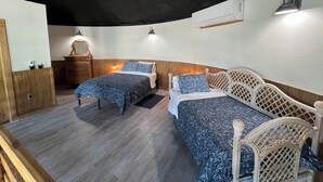 Une chambre avec deux lits, des meubles en bois et un ventilateur de plafond.