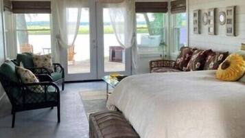 A bedroom with a large bed, a ceiling fan, and a view of the outdoors through a sliding door.