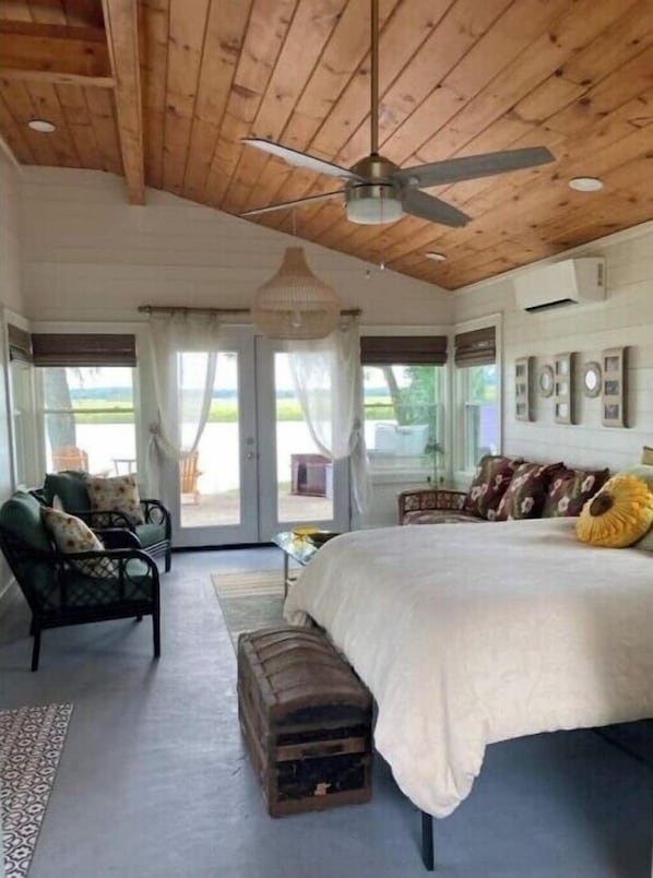 A bedroom with a large bed, a ceiling fan, and a view of the outdoors through a sliding door. - Paradise on the water. (Midway)