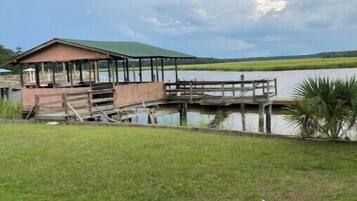 A wooden dock extending into a lake with a covered pavilion on the left.