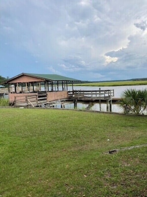 A wooden dock extending into a lake with a covered pavilion on the left. - Paradise on the water. (Midway)