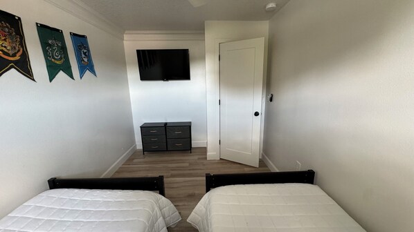 A bedroom with two beds, a dresser, and a TV on the wall. - 2Br Harry Potter Themed Home 7mins from Universal (Orlando)
