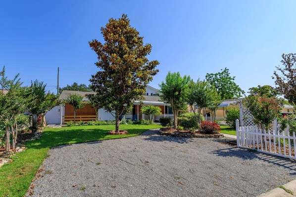 A residential area with houses, a gravel driveway, and a white picket fence.