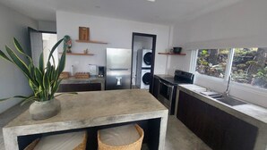 Una cocina compacta con lavadora integrada, un refrigerador y ventana con vista a un jardín.
