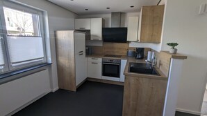 A compact kitchen with a refrigerator, oven, sink, and wooden cabinets.