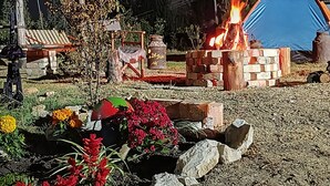 A campsite with a fire pit, a blue tent, and a rustic wooden structure. - LA TATA CABAÑA  ZON DE CAMPING  (Cucunubá)