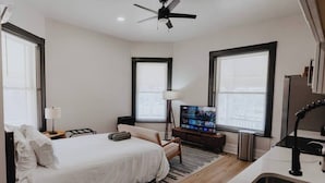 A hotel room with a bed, TV, desk, and a window.