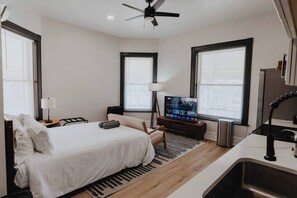 Habitación de hotel con cama, televisión, escritorio y ventana.