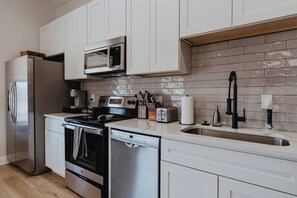 A modern kitchen with stainless steel appliances, white cabinetry, and a tiled backsplash. - Ground-Level Smart-Lock Studio · Walk to SSM-SLU Hospital · Free Street Parking (St. Louis)