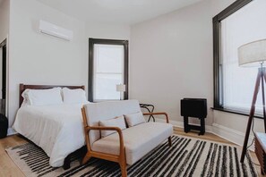 Un dormitorio con cama, sofá, lámpara y ventana.