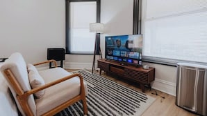 A living room with a sofa, a TV, a lamp, and a radiator.