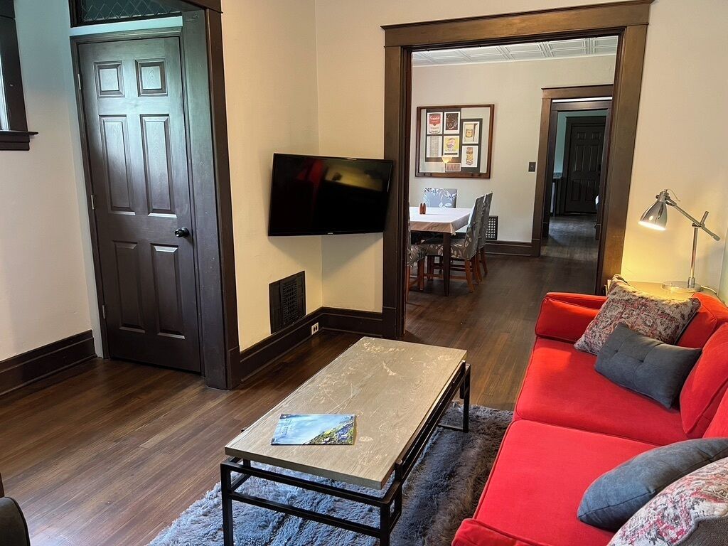 Ein Wohnzimmer mit einem roten Sofa, einem Couchtisch und einem Fernseher.