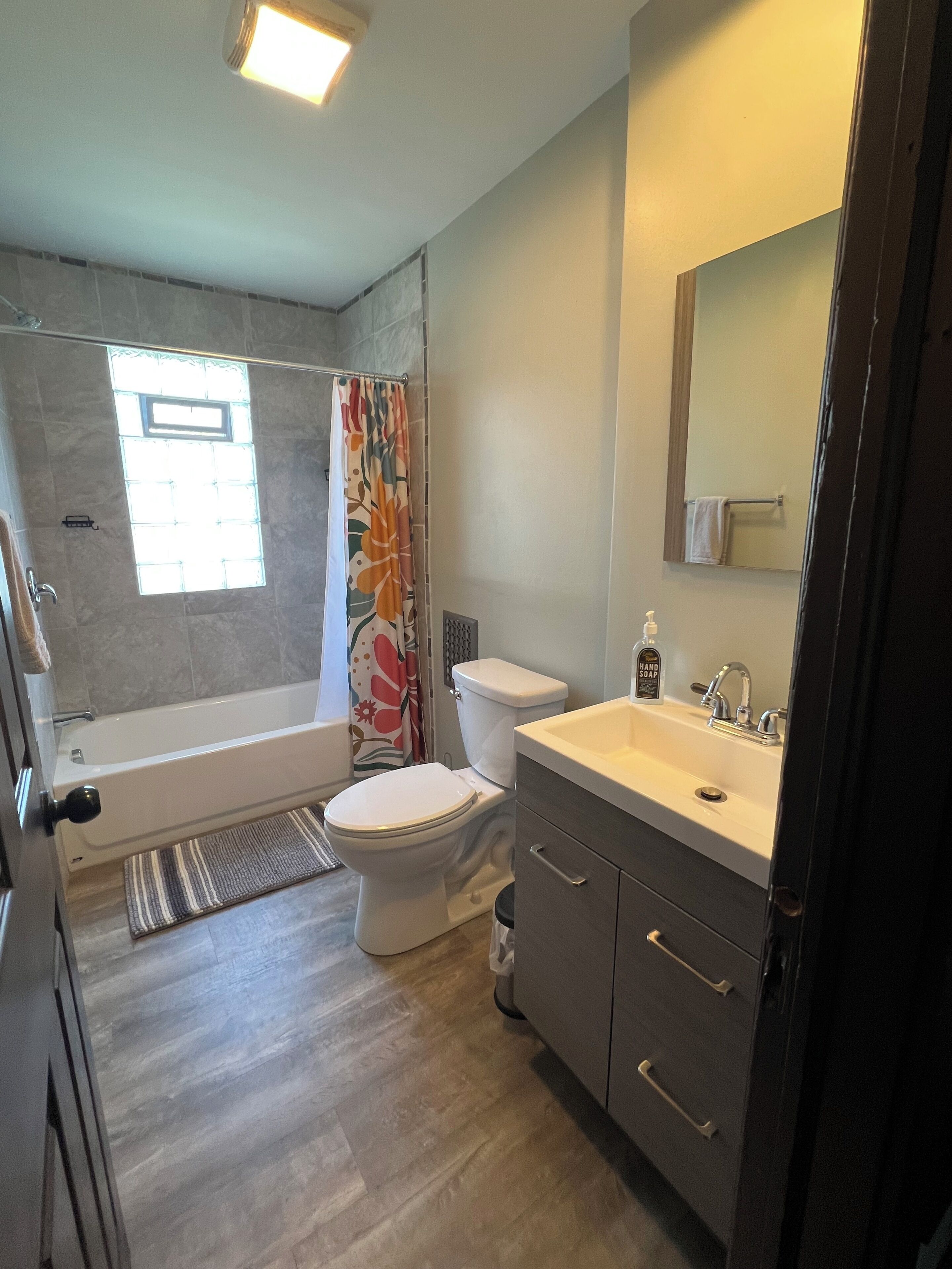 Une salle de bain avec une baignoire, des toilettes, un lavabo et une fenêtre.