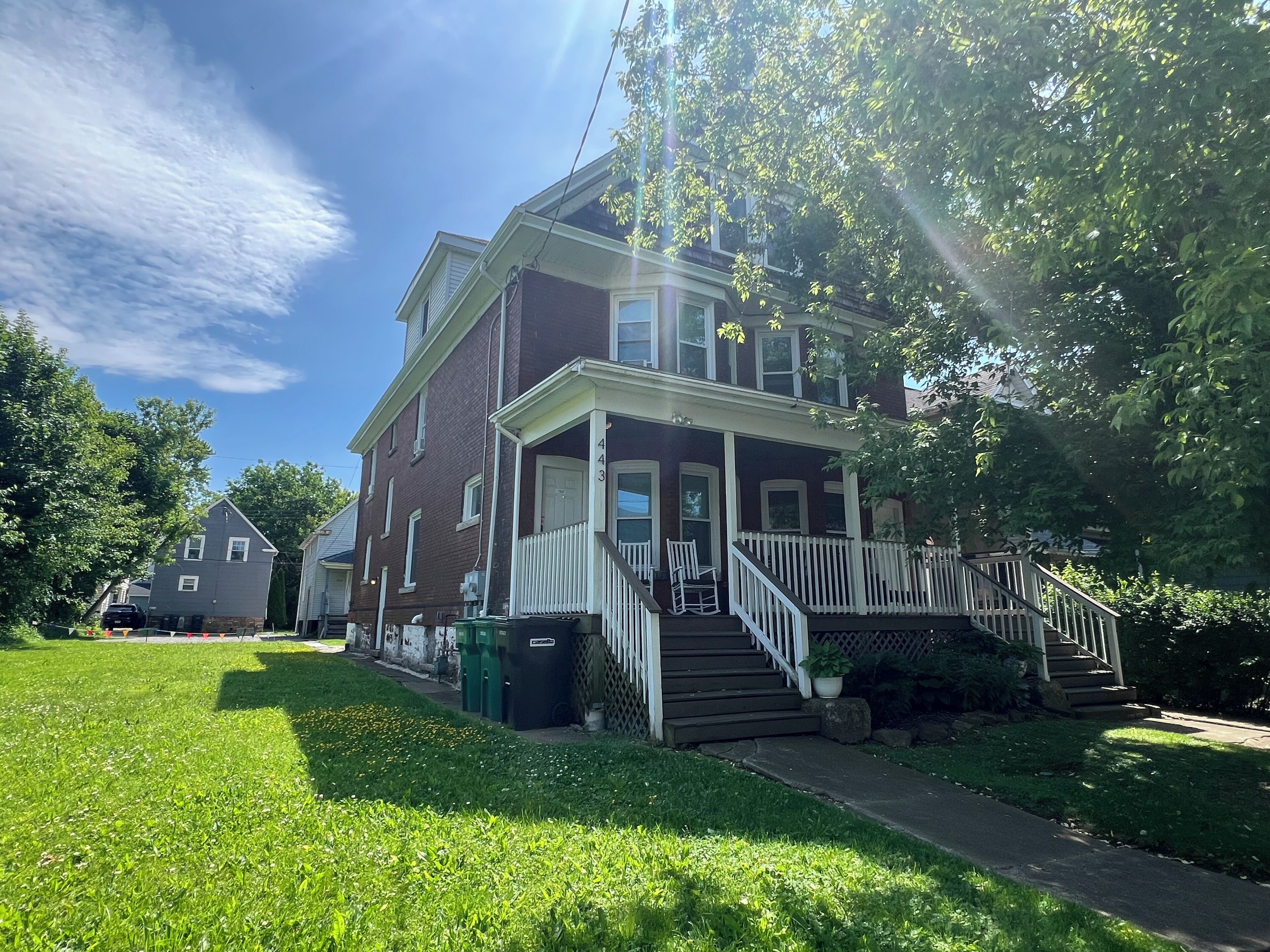 A two-story house with a front porch, a staircase, and a well-maintained lawn.