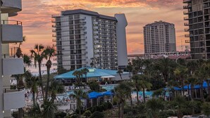 Un hotel con varios pisos, una zona de piscina y vistas al atardecer.