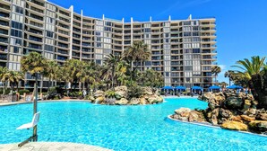 Un hotel con una gran piscina al aire libre rodeada de palmeras y rocas.