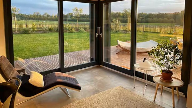 A modern room with a large sliding glass door leading to an outdoor deck.