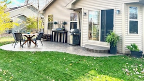 Una casa con patio, mobiliario exterior y una parrilla.