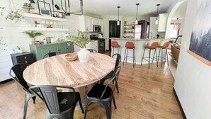 Una cocina moderna con armarios blancos, una isla central con taburetes y una mesa de comedor con sillas.
