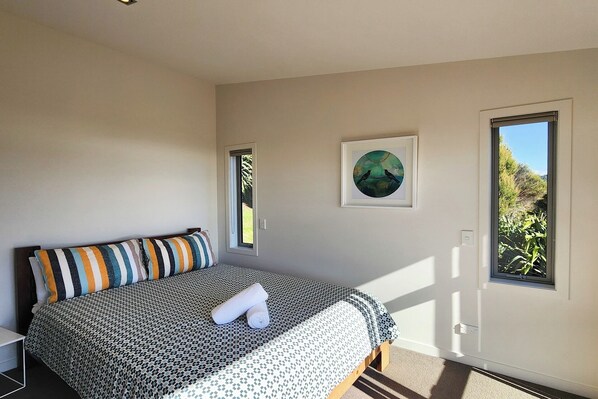 Un dormitorio con cama, ventana y un cuadro en la pared.