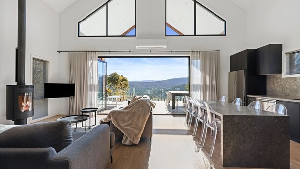 A modern living room with a fireplace, a dining area, and a kitchen.