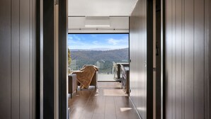A modern interior with a view of a mountainous landscape through a glass door.