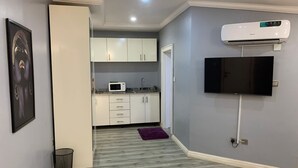 A modern kitchen with white cabinets, a microwave, and a purple rug.