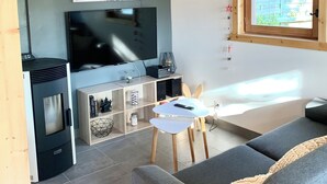 Un salon moderne doté d’un grand téléviseur à écran plat, d’un canapé, d’une petite table et d’un plafond en bois.