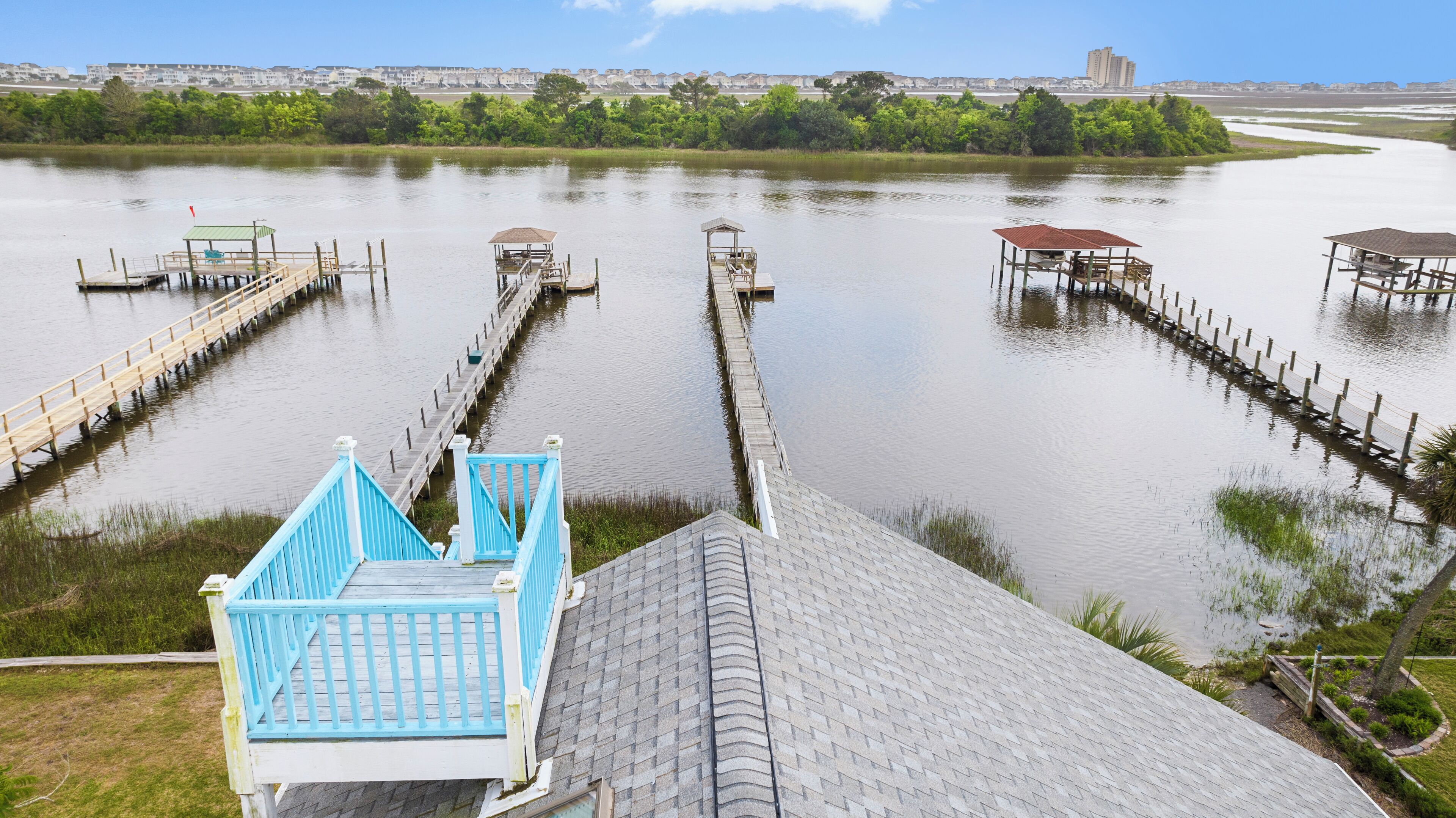 A waterfront property with multiple docks and a bridge leading to a grassy area.