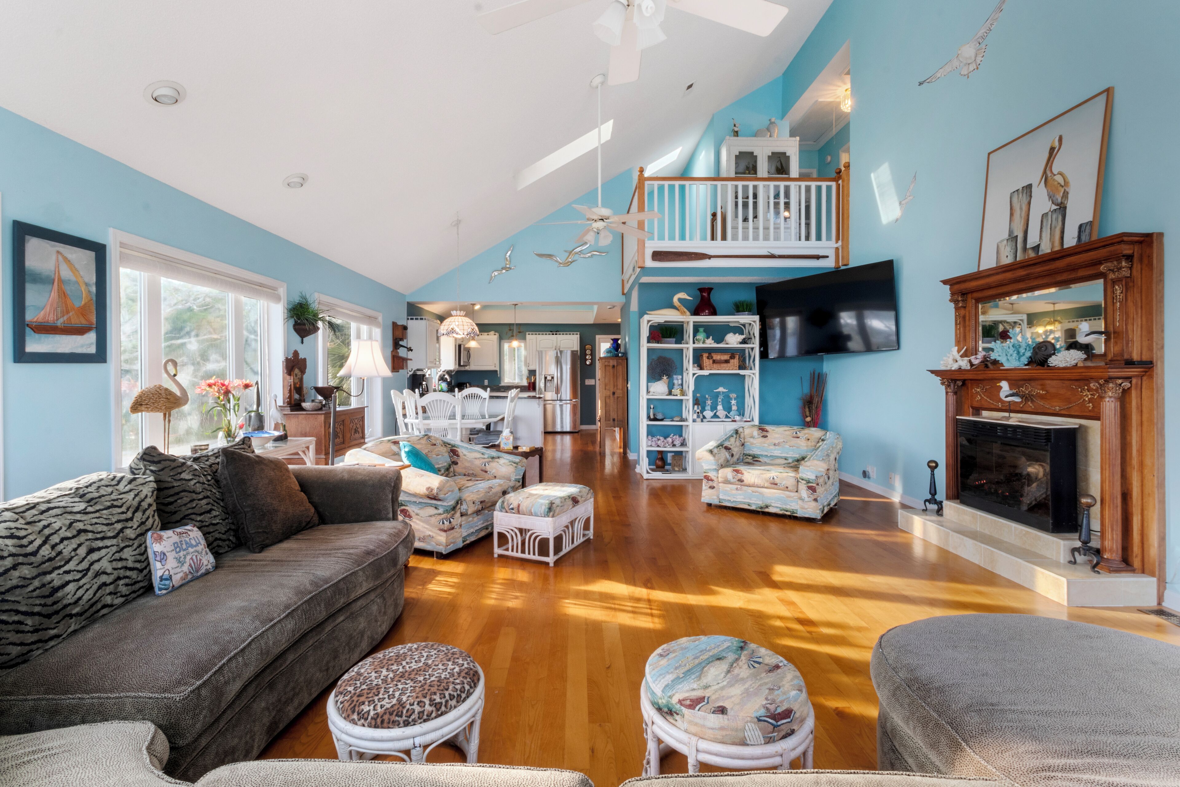 A spacious living room with a high ceiling, a wooden floor, and a cozy fireplace.