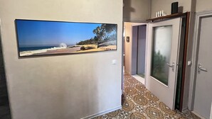 A hallway with a large beach painting, a patterned carpet, and a door with frosted glass. - Villa Egles - Villa with garden Lignano Sabbiadoro (Lignano Sabbiadoro)
