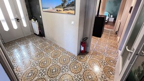 A hallway with patterned flooring, a fire extinguisher, a radiator, and a framed picture on the wall. - Villa Egles - Villa with garden Lignano Sabbiadoro (Lignano Sabbiadoro)