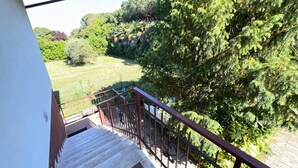 A staircase with a metal railing leading to a balcony overlooking a grassy area with trees. - Villa Egles - Villa with garden Lignano Sabbiadoro (Lignano Sabbiadoro)