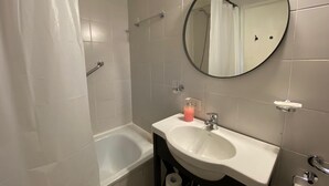 Une salle de bain avec une baignoire, un lavabo, un miroir et un rideau de douche.