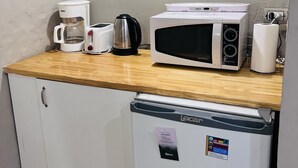 Une petite cuisine équipée d’un four à micro-ondes, d’une machine à café, d’un grille-pain et d’un petit réfrigérateur.