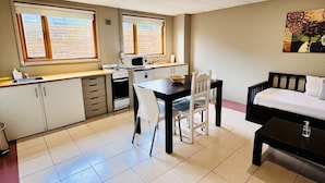 Una habitación compacta con kitchenette, comedor y cama.