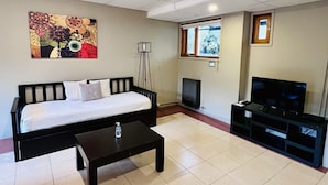 Una habitación de hotel con una cama, una mesita de centro, un televisor, un cuadro en la pared y una ventana con vistas a árboles.