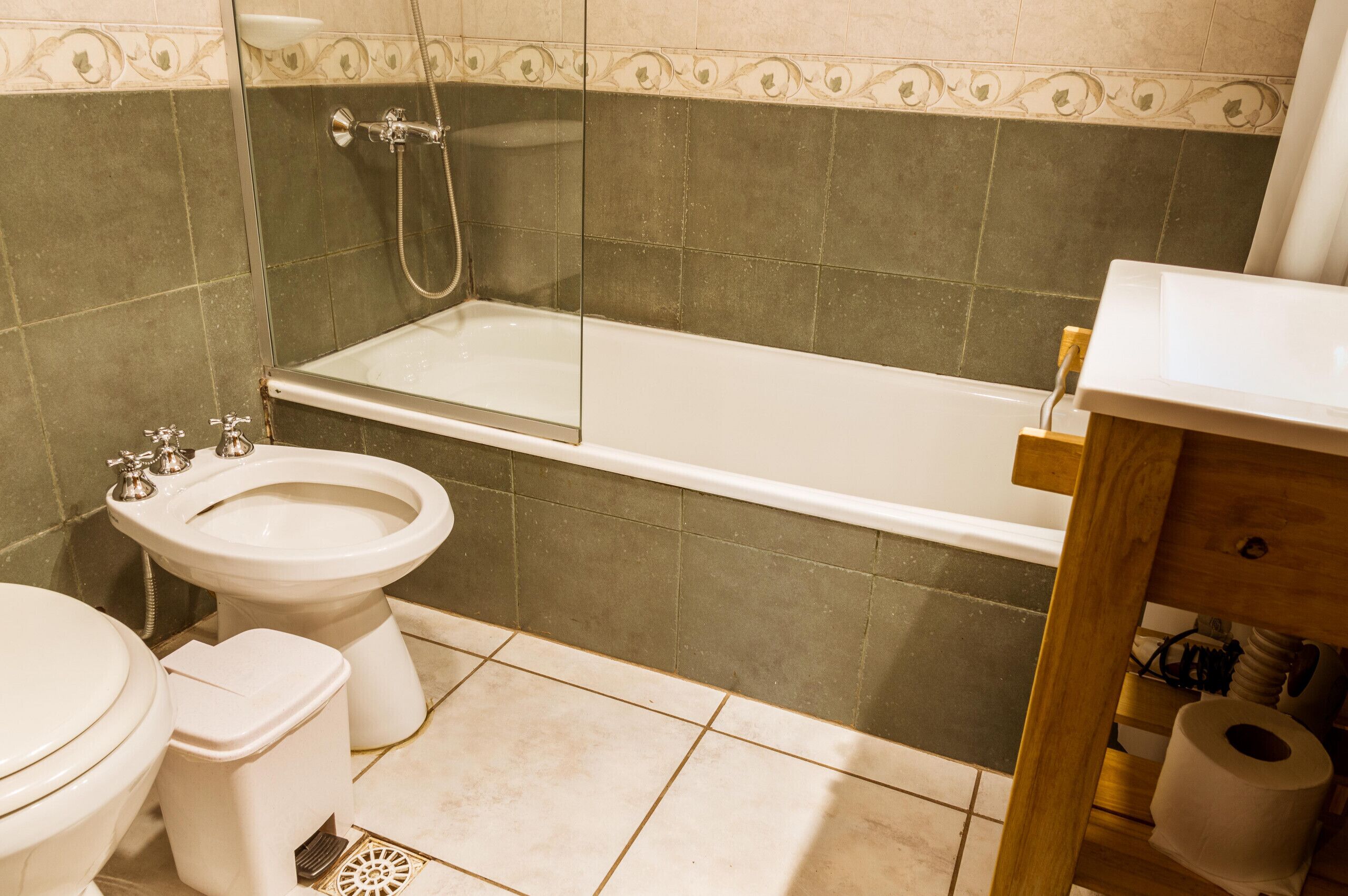 Ein Badezimmer mit einer Badewanne, Toilette, Bidet und einem Holzausstattung mit Waschbecken.