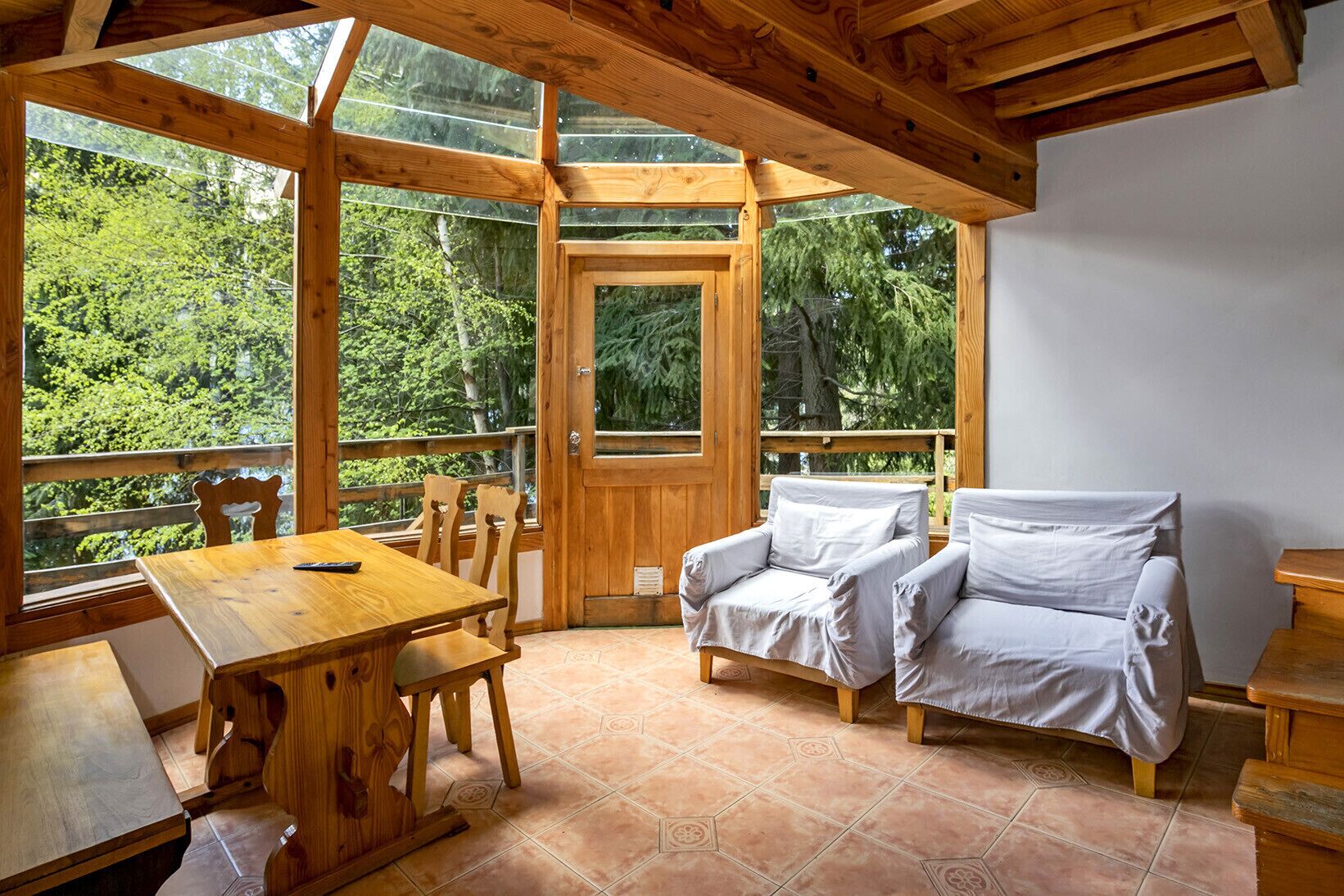 A wooden cabin with a dining table, chairs, and a sofa.