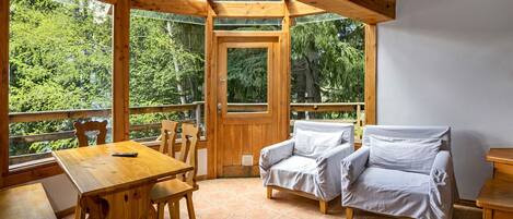 A wooden cabin with a dining table, chairs, and a sofa.