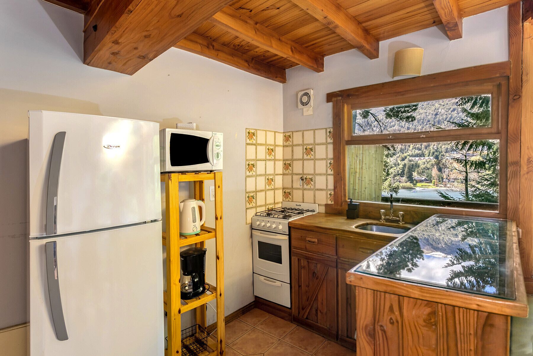 Cocina compacta con refrigerador, microondas, hervidor de agua, cafetera, estufa y pileta.
