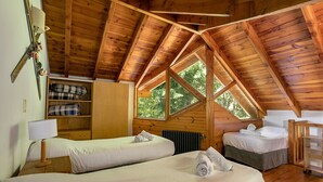 Una cabaña acogedora con dos camas, techo de madera y un ventanal grande.