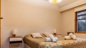 A neatly arranged bedroom with a bed, bedside lamps, and a window with a view.